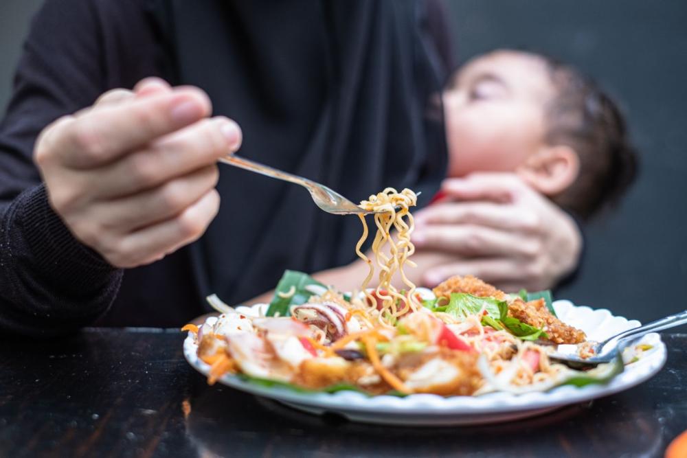 Postpartum Nutrition mom eating holding baby